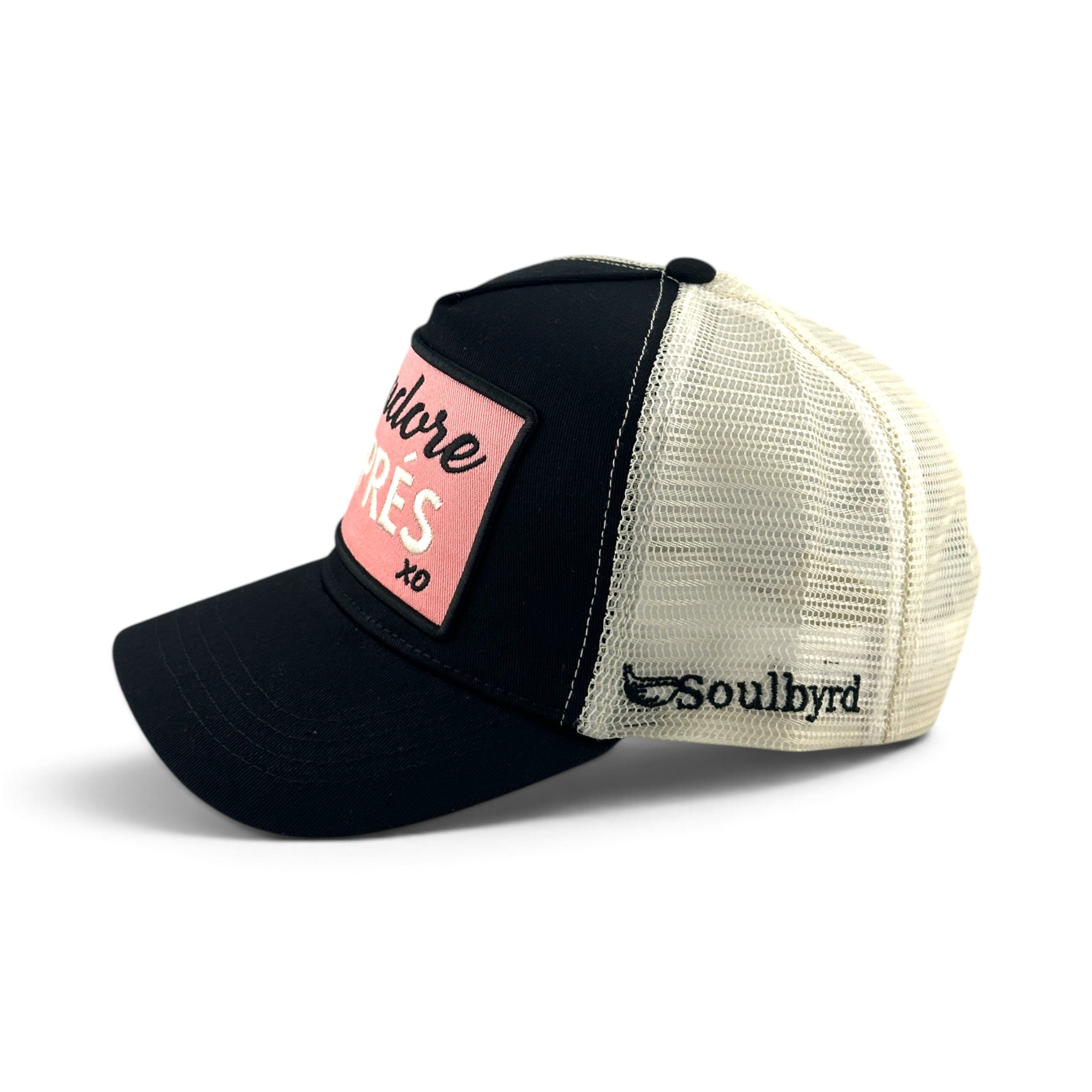 Soulbyrd Wholesale black cotton trucker hat with a pink patch featuring J'adore Aprés text and white mesh back.