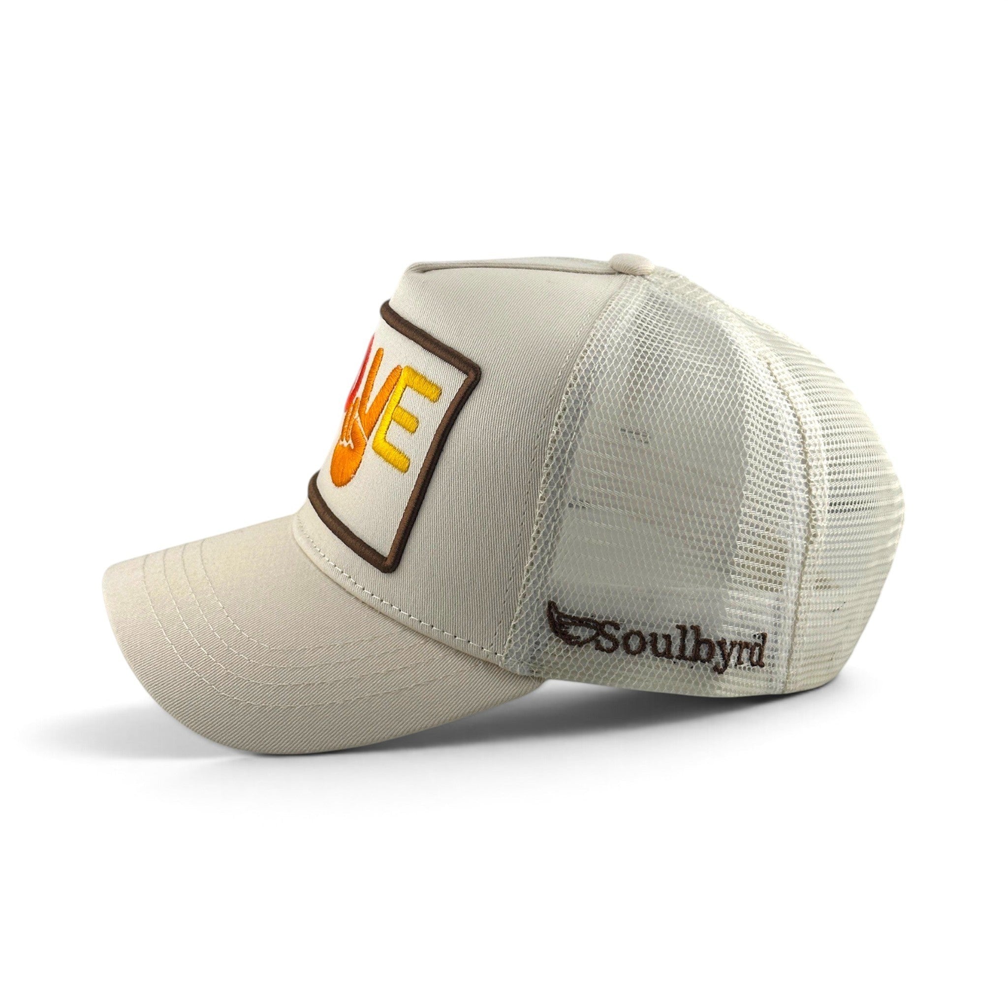 Soulbyrd Wholesale cream trucker hat with Love and Peace patch, cotton twill front, and breathable nylon mesh back.