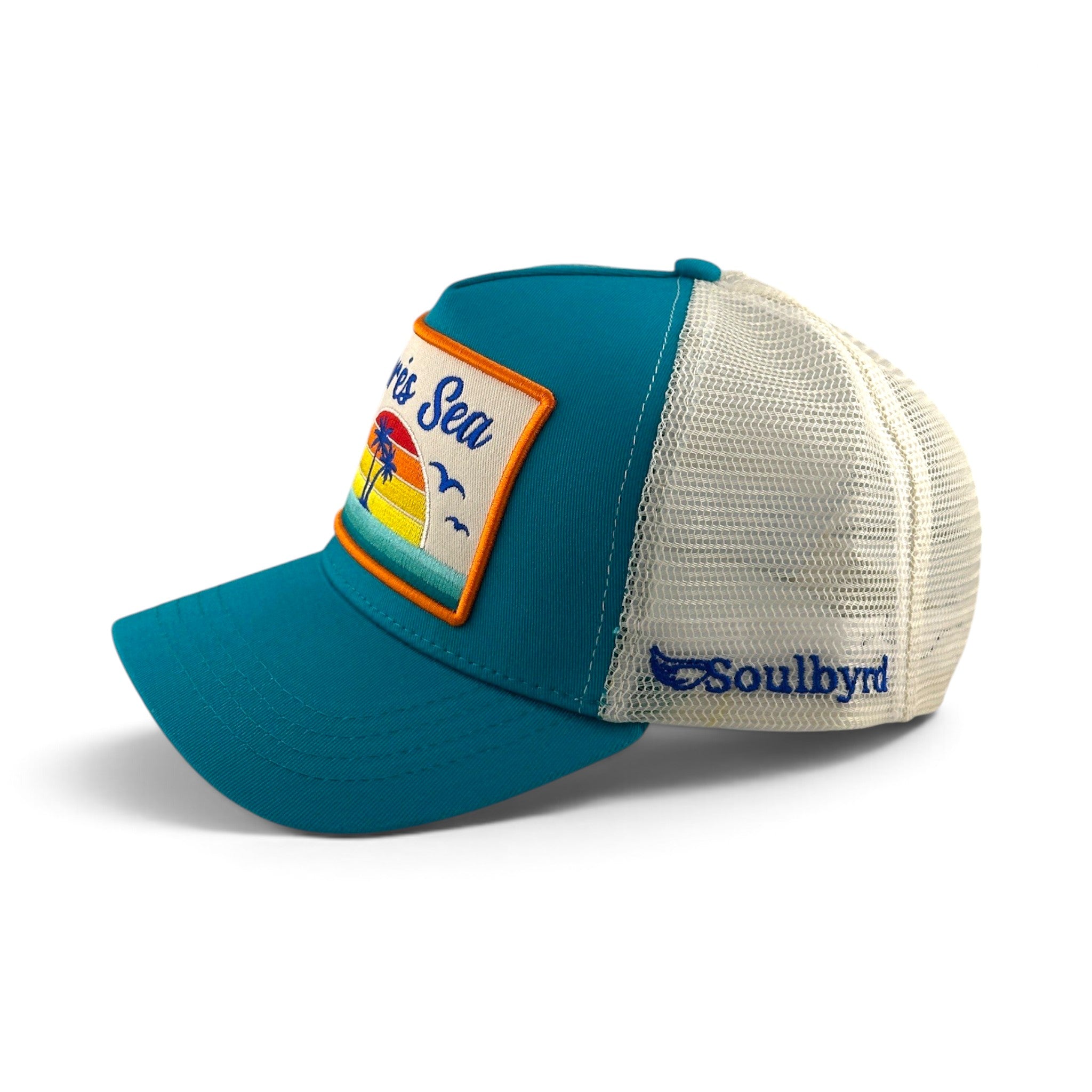 Soulbyrd Wholesale turquoise cotton trucker hat with white mesh back, featuring an Aprés Sea sunset patch.